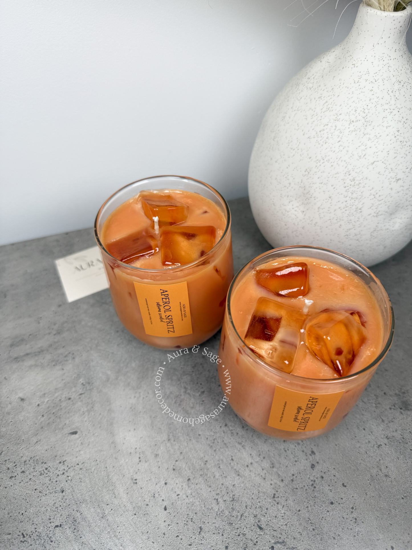 Aperol spritz drink-inspired candle in glass container.