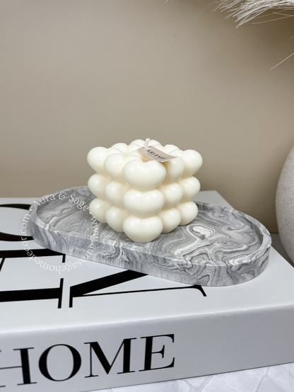 A white pillar soy candle with a bubble design, hand-poured and placed on a flat surface, with a grey and white marbled appearance.