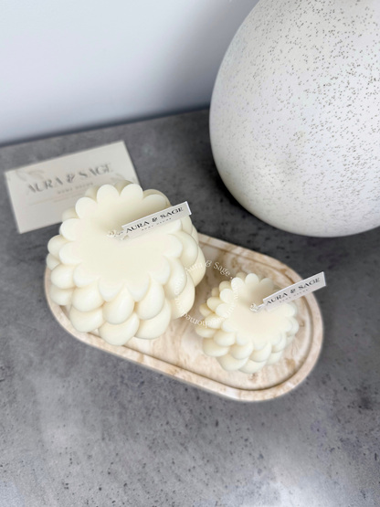 White decorative candles on a marble tray.